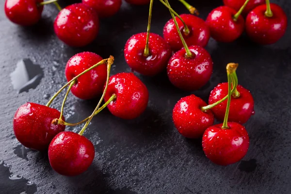 Cherries on a slate board. Sweet cherries on a dark background. Red berries in drops of water on black boards. Healthy food. Top view. Copy space