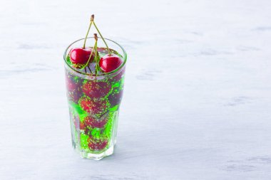 Vişne kokteyli. Beyaz arka plan üzerinde bir bardak kırmızı kiraz. Tatlı kiraz ile yeşil gazlı içecek. Kopyalama alanı