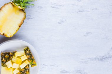 Gri bir arka plan üzerinde ananas dilimleri. Beyaz bir tabakta dilimlenmiş ananas. Vegan için tropikal meyve. Üst te. Kopyalama alanı