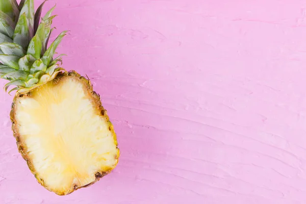 Pineapple on a pink background. Half of pineapple on a pastel background. Tropical fruit in a pop art style. Minimalism. Copy space