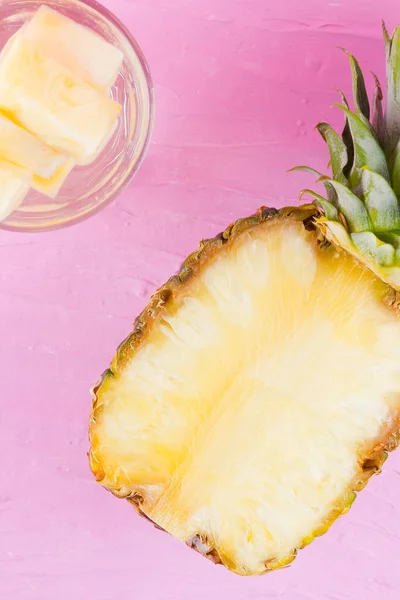 Pineapple and infused water on a pink background. Half of pineapple on a pastel background. Cocktail with pineapple and ice. Minimalism. Copy space