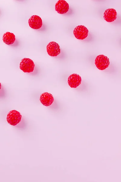 Pattern of raspberries on pink background. Colorful diet and healthy food concept. Background of raspberries. Top view. Flat lay. Copy space
