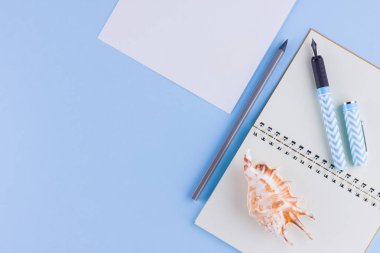 Okul konseptine geri dönelim. Okul kırtasiye ve mavi arka plan üzerinde deniz kabuğu. Pastel arka plan üzerine kalemler, kalem ve gon. Üst te. Kopyalama alanı