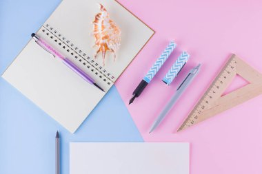 Okul konseptine geri dönelim. Okul kırtasiye ve pembe mavi arka plan üzerinde deniz kabuğu. Pastel arka plan üzerine kalemler, kalem ve gon. Üst te. Kopyalama alanı