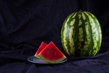 Siyah kumaş üzerine karpuz. Koyu zeminde bütün karpuz. Vegan için sağlıklı bir besin. Kopyalama alanı