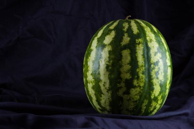 Siyah kumaş üzerine karpuz. Koyu zeminde bütün karpuz. Vegan için sağlıklı bir besin. Kopyalama alanı