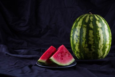 Siyah kumaş üzerine karpuz. Koyu zeminde bütün karpuz. Vegan için sağlıklı bir besin. Kopyalama alanı