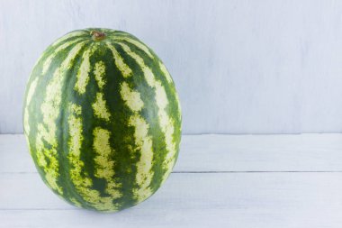 Doğal beyaz arka planda karpuz. Tahta zemin üzerine bütün karpuz. Vegan için sağlıklı bir besin. Kopyalama alanı