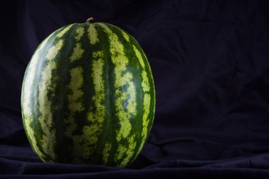 Siyah kumaş üzerine karpuz. Koyu zeminde bütün karpuz. Vegan için sağlıklı bir besin. Kopyalama alanı