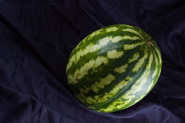 Siyah kumaş üzerine karpuz. Koyu zeminde bütün karpuz. Vegan için sağlıklı bir besin. Kopyalama alanı