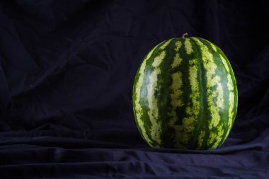 Siyah kumaş üzerine karpuz. Koyu zeminde bütün karpuz. Vegan için sağlıklı bir besin. Kopyalama alanı