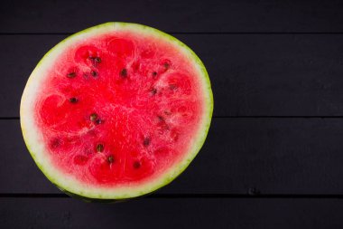 Tahta tahtalarda dilimlenmiş karpuz. Karpuzun yarısı koyu zeminde. Vegan için sağlıklı bir besin. Üstte görüntü