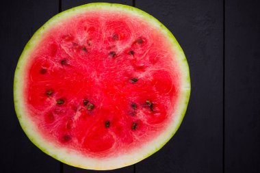 Tahta tahtalarda dilimlenmiş karpuz. Karpuzun yarısı koyu zeminde. Vegan için sağlıklı bir besin. Üstte görüntü