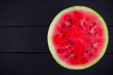 Tahta tahtalarda dilimlenmiş karpuz. Karpuzun yarısı koyu zeminde. Vegan için sağlıklı bir besin. Üstte görüntü