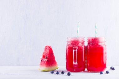 Karpuz dilimleri ile mason kavanozlarda karpuz içmek. Beyaz arka planda karpuz smoothies ve yaban mersini. Vejetaryen için yaz sağlıklı içecek. Kopyalama alanı