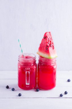 Karpuz dilimleri ile mason kavanozlarda karpuz içmek. Beyaz arka planda karpuz smoothies ve yaban mersini. Vejetaryen için yaz sağlıklı içecek. Kopyalama alanı
