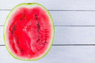 Beyaz arka planda karpuzun yarısı. Tahta tahtalarda dilimlenmiş karpuz. Vegan için sağlıklı bir besin. Üstte görüntü