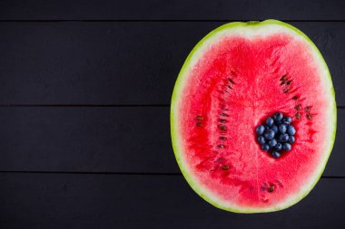 Karpuz ve koyu arka planda yaban mersini. Karpuzda yaban mersini. Yaratıcı gıda konsepti. Üstte görüntü