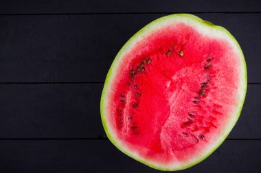 Karpuzun yarısı koyu zeminde. Tahta tahtalarda dilimlenmiş karpuz. Vegan için sağlıklı bir besin. Üstte görüntü