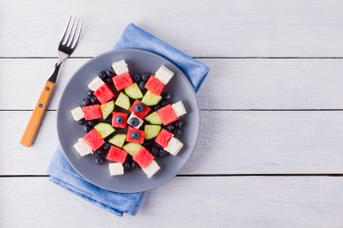 Mavi peçete üzerinde beyaz peynir li karpuz salatası. Yaban mersini, salatalık, karpuz ve peynir ile sağlıklı salata. Gri tabak ve çatal üzerine yaz salatası