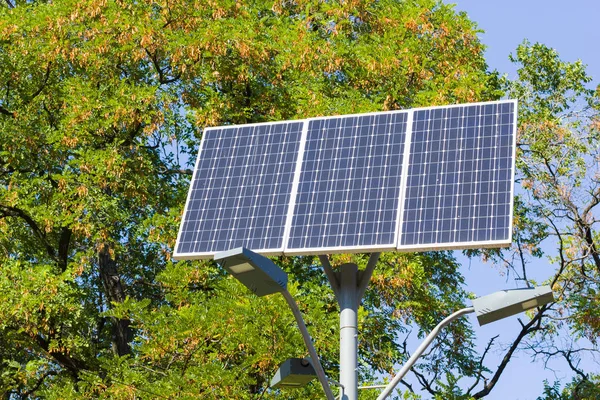 Solar device with street lamp on background of blue sky. Street light powered by solar panel with battery included. Alternative energy from the sun