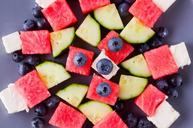 Beyaz peynirli karpuz salatası. Yaban mersini, salatalık, karpuz ve peynir ile sağlıklı salata. Gri tabakta yaz salatası