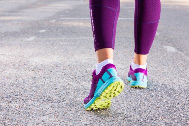 Spor ayakkabıyla koşan sportif bir kadın. Koşucu ayakları yolda koşuyor ayakkabıya yakın. Genç fitness kadını sabah koşuyor. Fitness sağlıklı yaşam konsepti