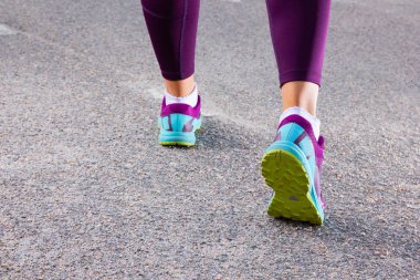 Spor ayakkabıyla koşan sportif bir kadın. Koşucu ayakları yolda koşuyor ayakkabıya yakın. Genç fitness kadını sabah koşuyor. Fitness ve egzersiz sağlıklı yaşam konsepti