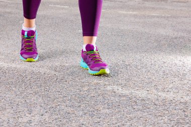 Spor ayakkabıyla koşan sportif bir kadın. Koşucu ayakları yolda koşuyor ayakkabıya yakın. Genç fitness kadını sabah koşuyor. Fitness ve egzersiz sağlıklı yaşam konsepti