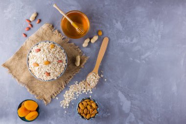 Sağlıklı bir kahvaltı için malzemeler, fındık, yulaf ezmesi, bal, kurutulmuş kayısı, badem, fıstık. Mevsimlik doğal organik gıda kavramı. Çuval bezinde yulaf ezmesi