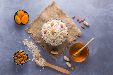 Sağlıklı bir kahvaltı için malzemeler, fındık, yulaf ezmesi, bal, kurutulmuş kayısı, badem, fıstık. Mevsimlik doğal organik gıda kavramı. Çuval bezinde yulaf ezmesi