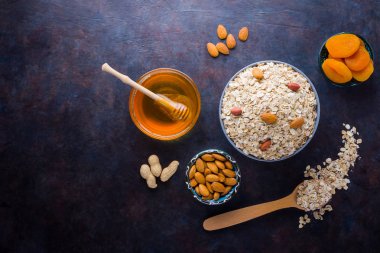Sağlıklı bir kahvaltı için yulaf ezmesi ve fındık. Kasede yulaf ezmesi ve bal. Kuru yulaf ezmesi, badem ve kurutulmuş kayısı. Yiyecek konsepti