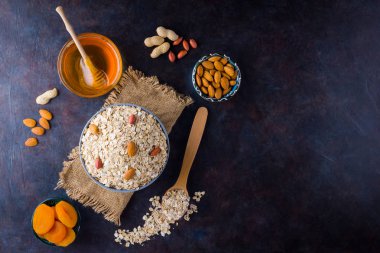 Çuval bezinde yulaf ezmesi ve fındık. Kasede yulaf ezmesi ve bal. Kuru yulaf ezmesi, badem ve kurutulmuş kayısı. Yiyecek konsepti