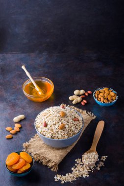 Çuval bezinde yulaf ezmesi ve fındık. Kasede yulaf ezmesi ve bal. Kuru yulaf ezmesi, badem ve kurutulmuş kayısı. Yiyecek konsepti