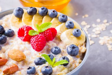 Kahvaltıda yulaf ezmesi ve fındık. Meyveli, fındıklı ve ballı yulaf ezmesi. Yabanmersinli yulaf ezmesi, muz ve ahududu. Sağlıklı yemek.