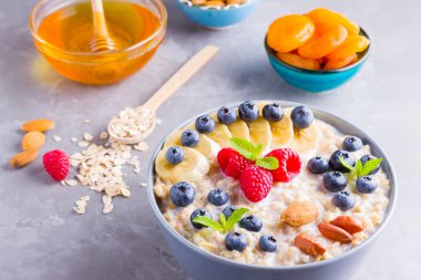 Kahvaltıda yulaf ezmesi ve fındık. Meyveli, fındıklı ve ballı yulaf ezmesi. Yabanmersinli yulaf ezmesi, muz ve ahududu. Sağlıklı yemek.