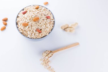 Beyaz arka planda kuru yulaf ezmesi ve fındık. Sağlıklı kahvaltı için gerekenler: badem, fıstık ve yulaf ezmesi. Boşluğu kopyala
