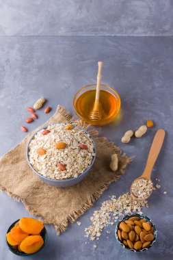 Sağlıklı bir kahvaltı için malzemeler, fındık, yulaf ezmesi, bal, kurutulmuş kayısı, badem, fıstık. Mevsimlik doğal organik gıda kavramı. Çuval bezinde yulaf ezmesi