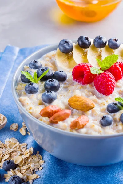 Healthy homemade oatmeal with berries and nuts for breakfast. Oatmeal with fruits, nuts and honey. Oatmeal with blueberries, banana and raspberries