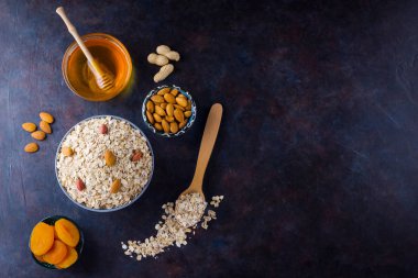 Sağlıklı bir kahvaltı için yulaf ezmesi ve fındık. Kasede yulaf ezmesi ve bal. Kuru yulaf ezmesi, badem ve kurutulmuş kayısı. Yiyecek konsepti