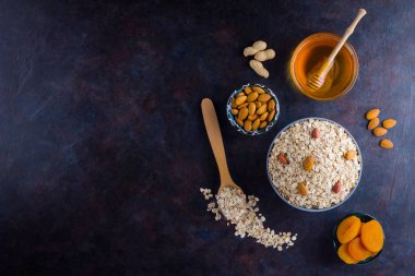 Sağlıklı bir kahvaltı için yulaf ezmesi ve fındık. Kasede yulaf ezmesi ve bal. Kuru yulaf ezmesi, badem ve kurutulmuş kayısı. Yiyecek konsepti