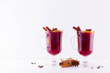 Beyaz arka planda baharatlı sıcak sıcak şarap. Noel şarabı portakallı, yıldız anason ve tarçınlı. İki bardak kış Noel içkisi.