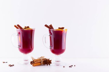 Beyaz arka planda baharatlı sıcak sıcak şarap. Noel şarabı portakallı, yıldız anason ve tarçınlı. İki bardak kış Noel içkisi.