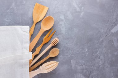 Sıfır atık. Pamuk eko çanta ve gri arka planda ahşap çatal bıçak takımı. Çevre dostu ahşap çatal bıçak takımı. Plastiksiz konsept. Minimalizm. Üst Manzara. Boşluğu kopyala