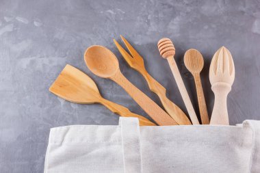 Sıfır atık. Pamuk eko çanta ve gri arka planda ahşap çatal bıçak takımı. Çevre dostu ahşap çatal bıçak takımı. Plastiksiz konsept. Minimalizm. Üst Manzara. Boşluğu kopyala