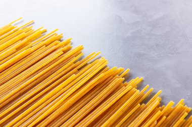 Gri arka planda sarı makarna. Çimento arka planında spagetti. Çiğ spagetti bolonez. Yemek geçmişi konsepti. Üst görünüm