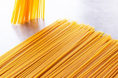 Gri arka planda sarı makarna. Çimento arka planında spagetti. Çiğ spagetti bolonez. Yemek geçmişi konsepti. Üst görünüm