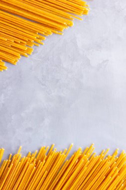 Gri arka planda sarı makarna. Çimento arka planında spagetti. Çiğ spagetti bolonez. Yemek geçmişi konsepti. Üst görünüm