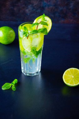 Limonlu mojito kokteyli ve uzun bardakta nane şekeri. Koyu arkaplanda cam içinde taze mojito. Naneli kokteyli limonla tazeliyorum. Erimiş su.