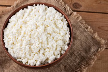 Çuval bezinde süzme peynir. Kâsede taze süzme peynir. Tahtadaki yumuşak peynir. Üst Manzara. Boşluğu kopyala